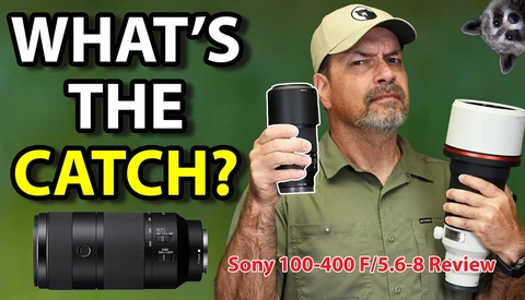 Reviewer holding Sony 100-400mm F/5.6-8 telephoto lens and camera against green background
