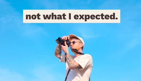 Photographer with camera and sunglasses against blue sky, with text overlay reading 'not what I expected'