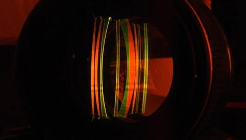 Colorful fiber optic cables glowing inside a dark cylindrical structure with warm red ambient lighting