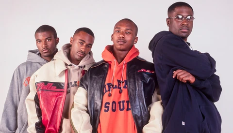 Four men in casual streetwear posed together against a neutral background