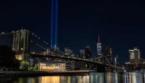 Brooklyn Bridge and Manhattan skyline at night with Tribute in Light beams