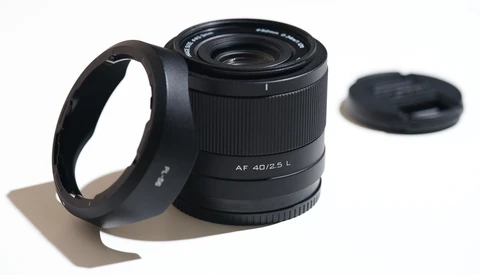 AF 40/2.5 L lens with hood and rear cap on neutral background