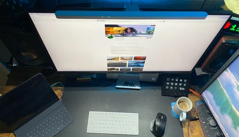 Photographer's desk setup with monitor displaying portfolio website, keyboard, mouse, and coffee cup