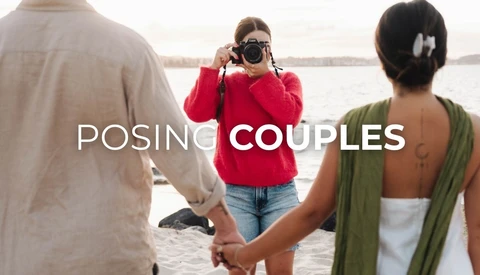 Photographer in red jacket taking portrait of couple holding hands by waterside