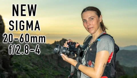 Photographer holding mirrorless camera with landscape backdrop at golden hour