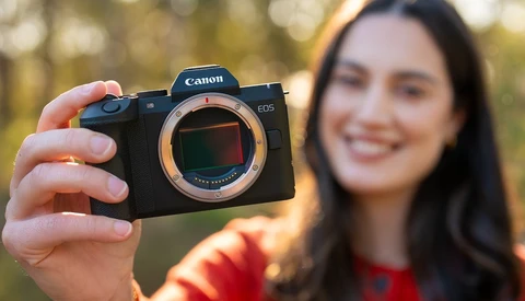 Woman holding Canon EOS mirrorless camera with sensor exposed to camera