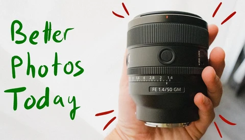 Hand holding a Sony FE 1.4/50 GM prime lens against a white background