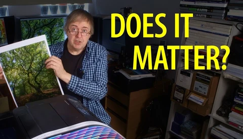 Man holding framed landscape print next to color-managed monitor in studio setting