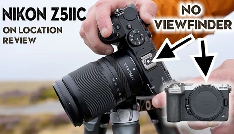 Nikon Z5IIC mirrorless camera held in hands with lens attached, shown from top angle against blurred outdoor background