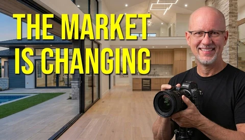 Photographer holding a Nikon DSLR camera inside a modern luxury home with open-concept living space