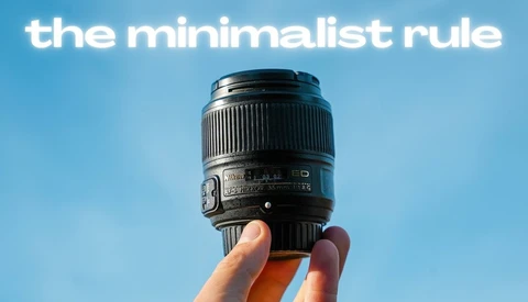 Hand holding a telephoto camera lens against a clear blue sky