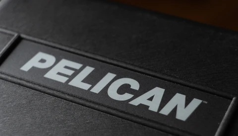 Logo for Pelican, white lettering on a black protective equipment case, shown in close-up at an angle.