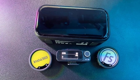 Mobile phone with two external lens attachments labeled Insta360 and FS, arranged on colorful gradient background