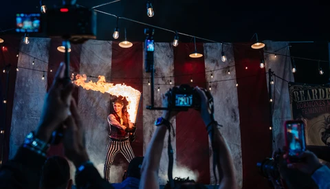Fire breather performer on stage with audience members recording on phones