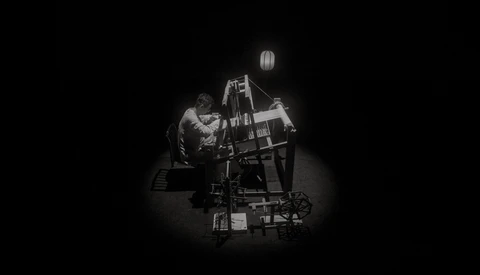 Cinematographer operating a film camera on a crane rig in dramatic studio lighting