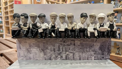 Twelve figurines in vintage work attire standing in a row on a cityscape base