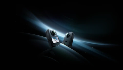 Two compact action cameras positioned facing each other against a dramatic dark background with glowing blue light rays