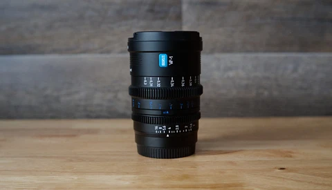 Black manual focus cinema lens with blue markings on wooden surface