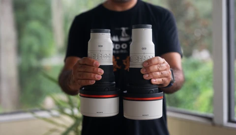 Photographer holding four white cylindrical lens cases with red accents