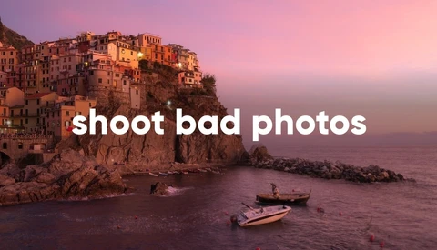 Coastal village perched on clifftop at sunset with boats in calm water below