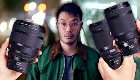 Photographer holding three telephoto lenses while wearing glasses and green jacket