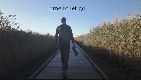 Person jogging away on wooden boardwalk through tall reeds with text overlay 'time to let go'