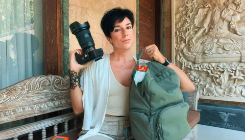 Photographer holding professional DSLR camera and green backpack in ornate interior space