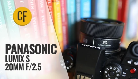 Panasonic Lumix S 20mm f/2.5 lens mounted on camera body with colorful book spines blurred in background