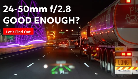 Highway night scene with truck and neon signs, with text overlay asking if a 24-50mm f/2.8 lens is adequate
