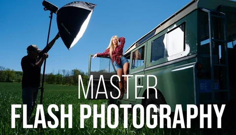 Photographer holding reflector while model poses on camper van in outdoor setting