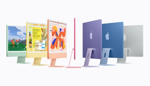 Row of colorful Apple iMac computers in green, yellow, orange, pink, purple, blue, and silver on a white background