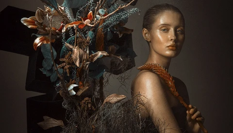 Portrait of a young woman with copper braid beside an ornate sculptural floral arrangement.