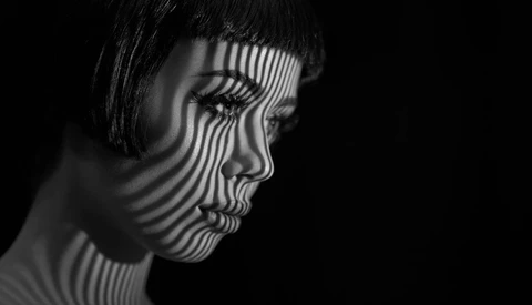 Profile of a woman's face with parallel linear striped shadow pattern across her features.