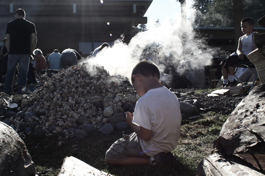 Young boy helps his tribe cook clams in the traditional way. Young boy helps his tribe cook clams in the traditional way.