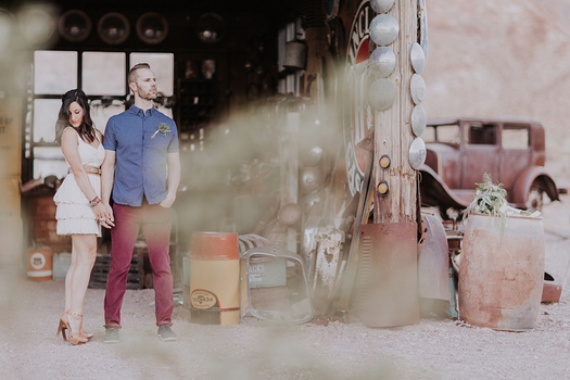 A bride and groom stand holding hands in vintage garage.