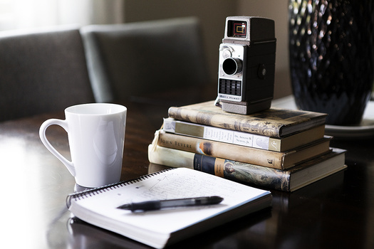 Notebook on desk with coffee and books