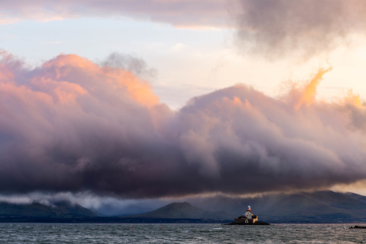 Photograph of a lighthouse under stormy skies during sunset