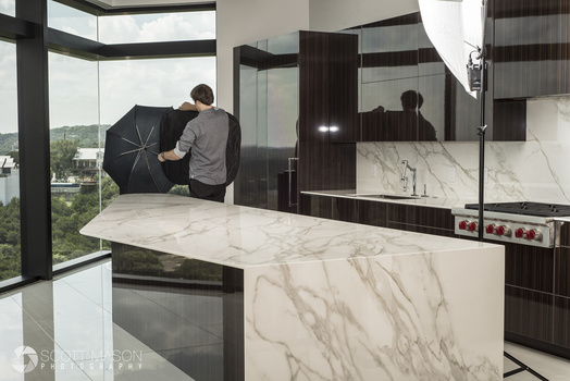 a behind-the-scenes photo of a man flagging off light from a kitchen interior