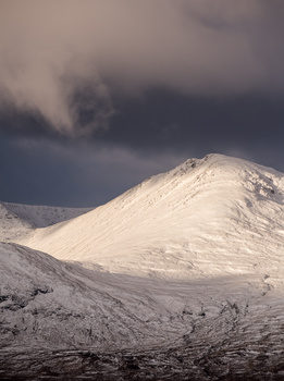 The strong juxtaposition between mountain and cloud creates a simple image Glen Coe mountain and snow