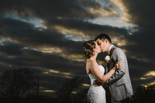 Couple kissing during sunset with dramatic clouds