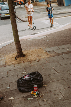 simple street photography projects for beginners A rubbish bag laying on the street with people walking by