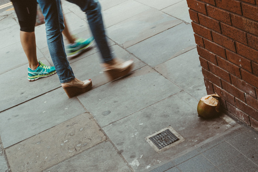 Simple street photography projects for beginners Two people walking by an old coconut on the ground