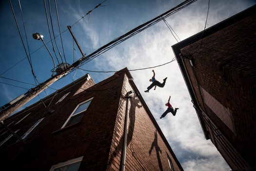 professional sports photography of parkour athletes jumping over rooftops