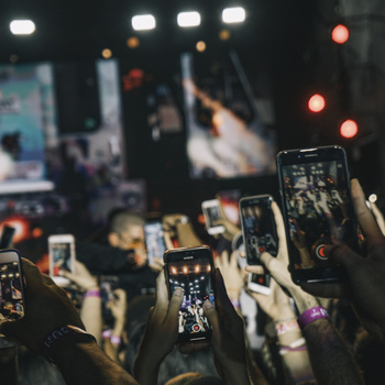 people holding up their smart phones at a concert