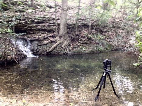 a photo showing a camera and tripod in water taking a waterfall picture