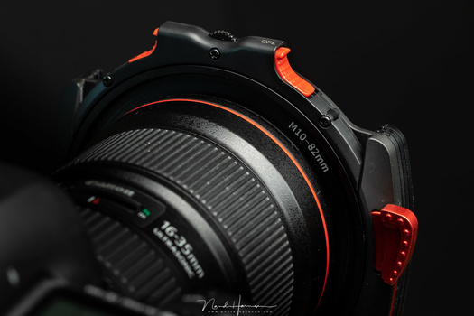 The filter holder is hold in place by a spring-loaded red lever. There is no risk of losing the filter holder with normal use. And by change it fits quite nicely with the red L-series lenses. I am sure it will also fit with the red accent of the Nikon cam