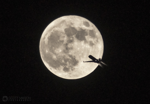 a silhouetted plane flying in front of the full moon