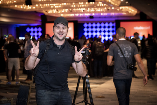 a videographer smiling and giving the peace sign at a conference