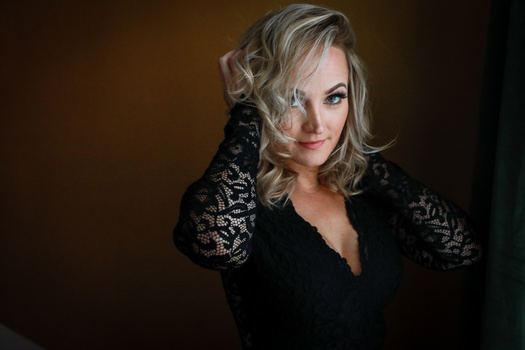 a woman with blonde hair posing in a lacey black dress