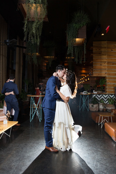 newlyweds kissing inside a venue with backlighting